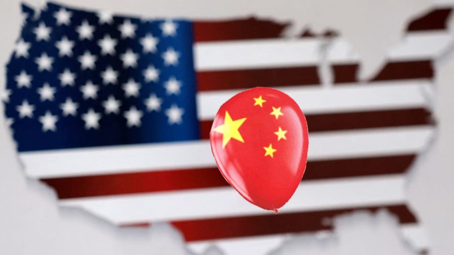 A printed balloon with Chinese flag is placed on a U.S. flag in the shape of U.S. map outline in an illustration.