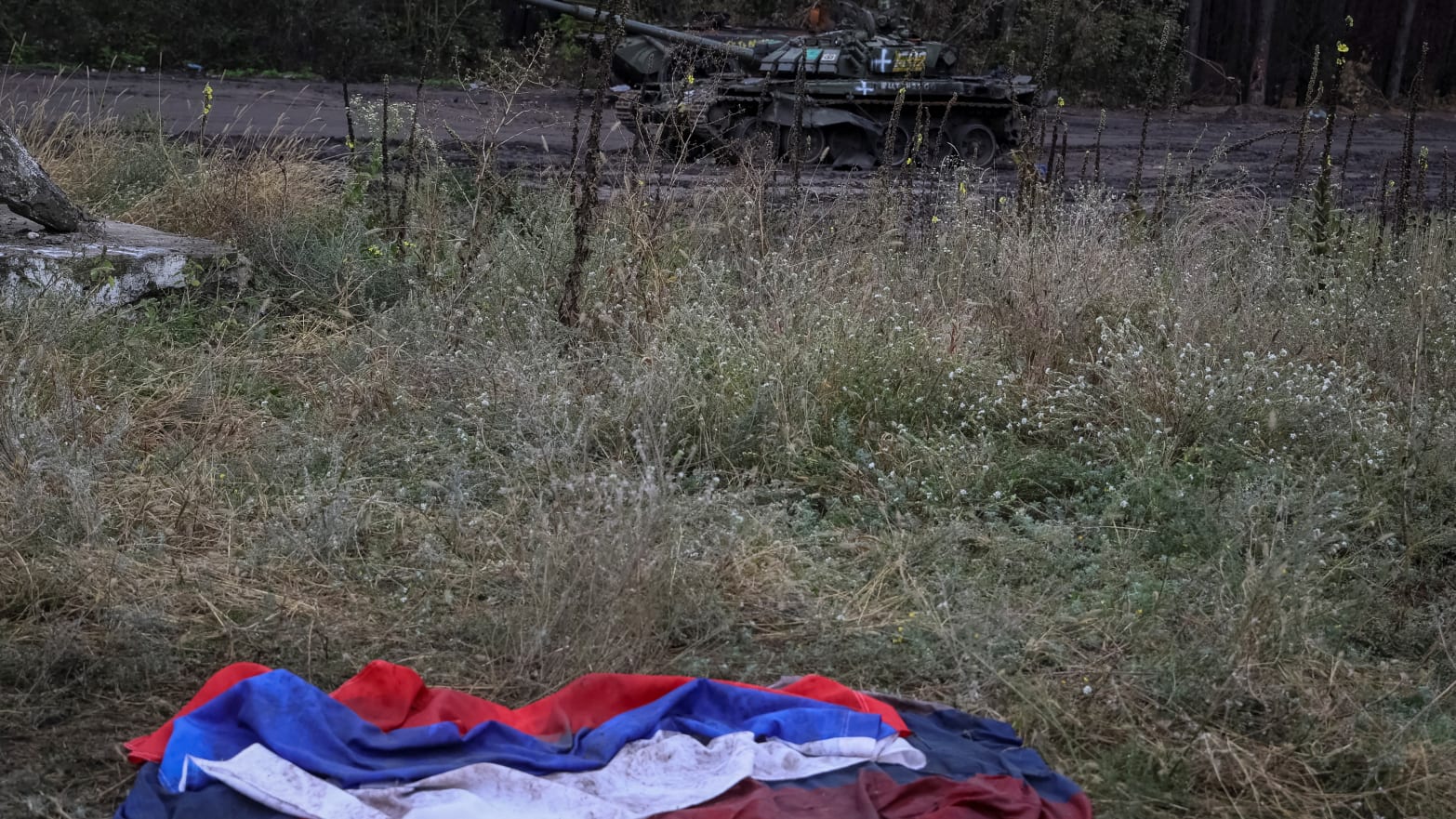 A Russian national flag lies on the ground near a destroyed Russian tank in the town of Izium, Ukraine, on Sept. 14, 2022.