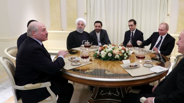 Russian President Vladimir Putin, Iranian President Hassan Rouhani, Turkish President Recep Tayyip Erdogan and President of Belarus Alexander Lukashenko sitting together at a table.