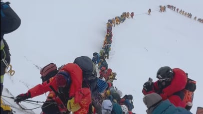 Dozens of climbers make their way up Mount Everest in a line