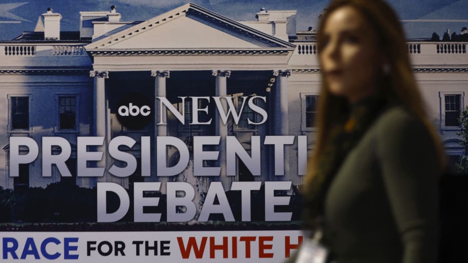 A person walks in front of a sign advertising the presidential debate.