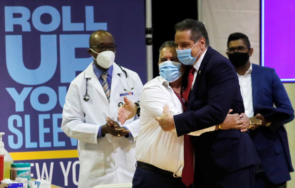 Andrew Cuomo in a mask hugs a man in a mask