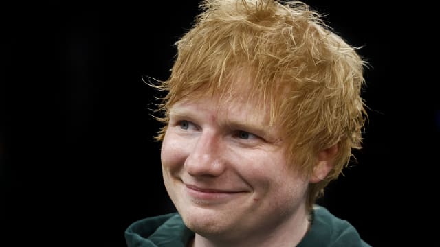 Ed Sheeran smiling in a green hoodie.