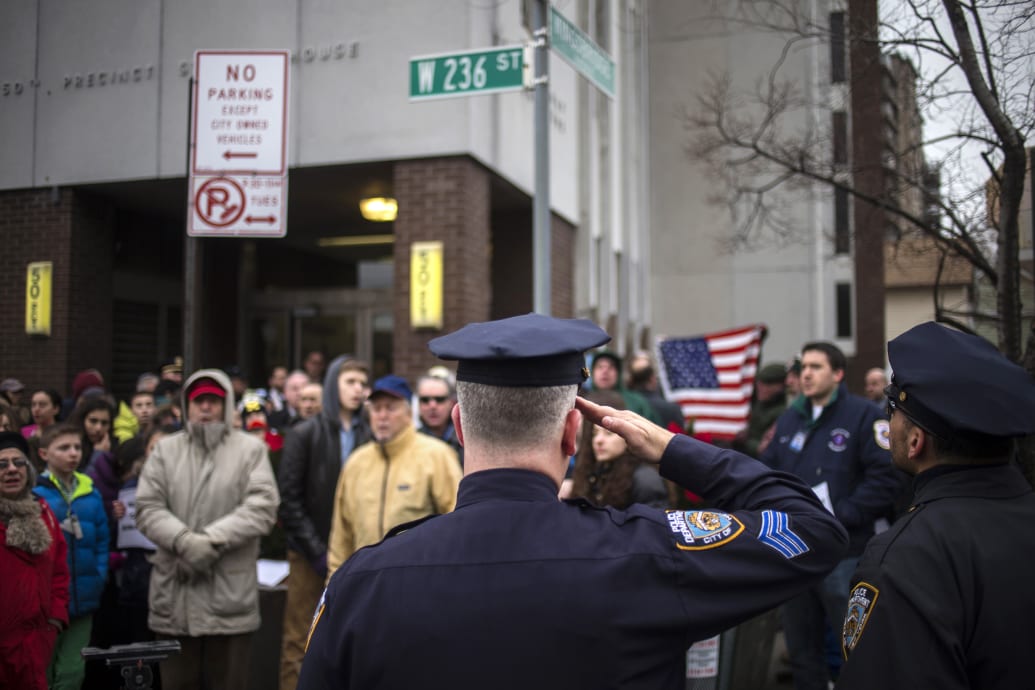 An NYPD sergeant salutes the American flag outside the 50th Precinct station house.