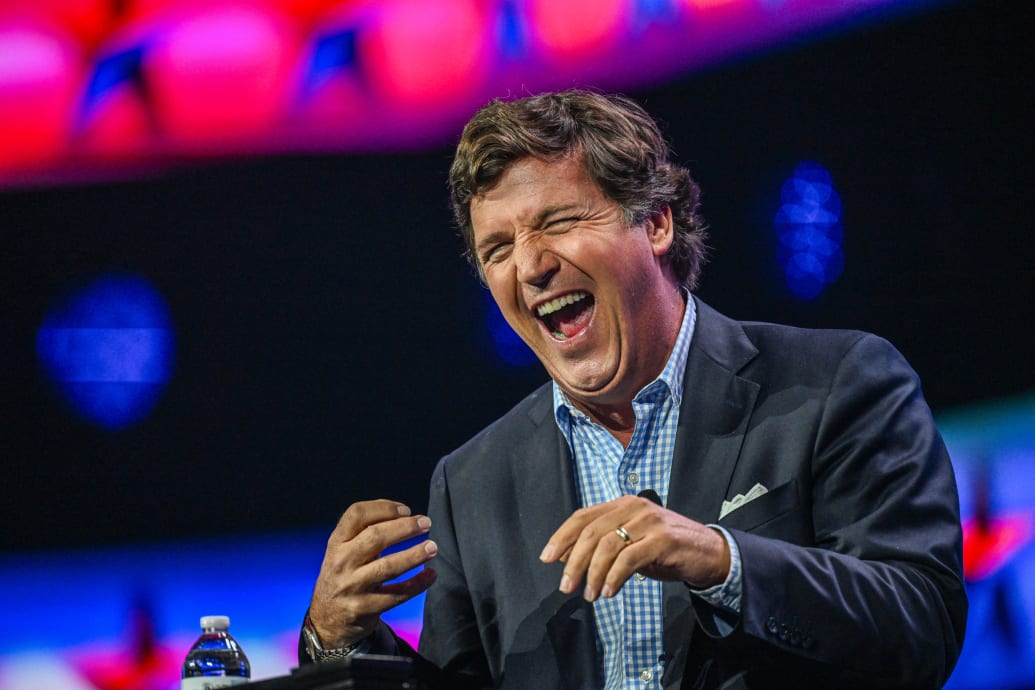 A photograph of Tucker Carlson laughing.