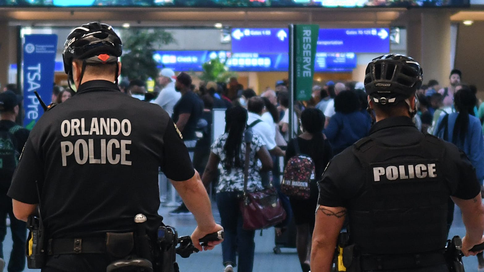 Police officers watch as travelers make their way through a TSA screening line at Orlando International Airport in July 2022.