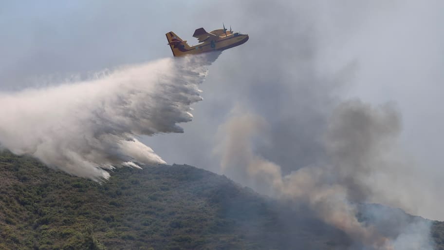 A firefighting plane makes a water drop, as a wildfire burns near the village of Vati, on the island of Rhodes, Greece. One water bomber has crashed on the island of Evia, according to authorities and shocking video.