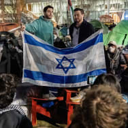 Two pro-Israel demonstrators stand on lawn chairs and argue with Palestine supporters at an encampment protest at Northeastern University, on Friday April 26, 2024. 