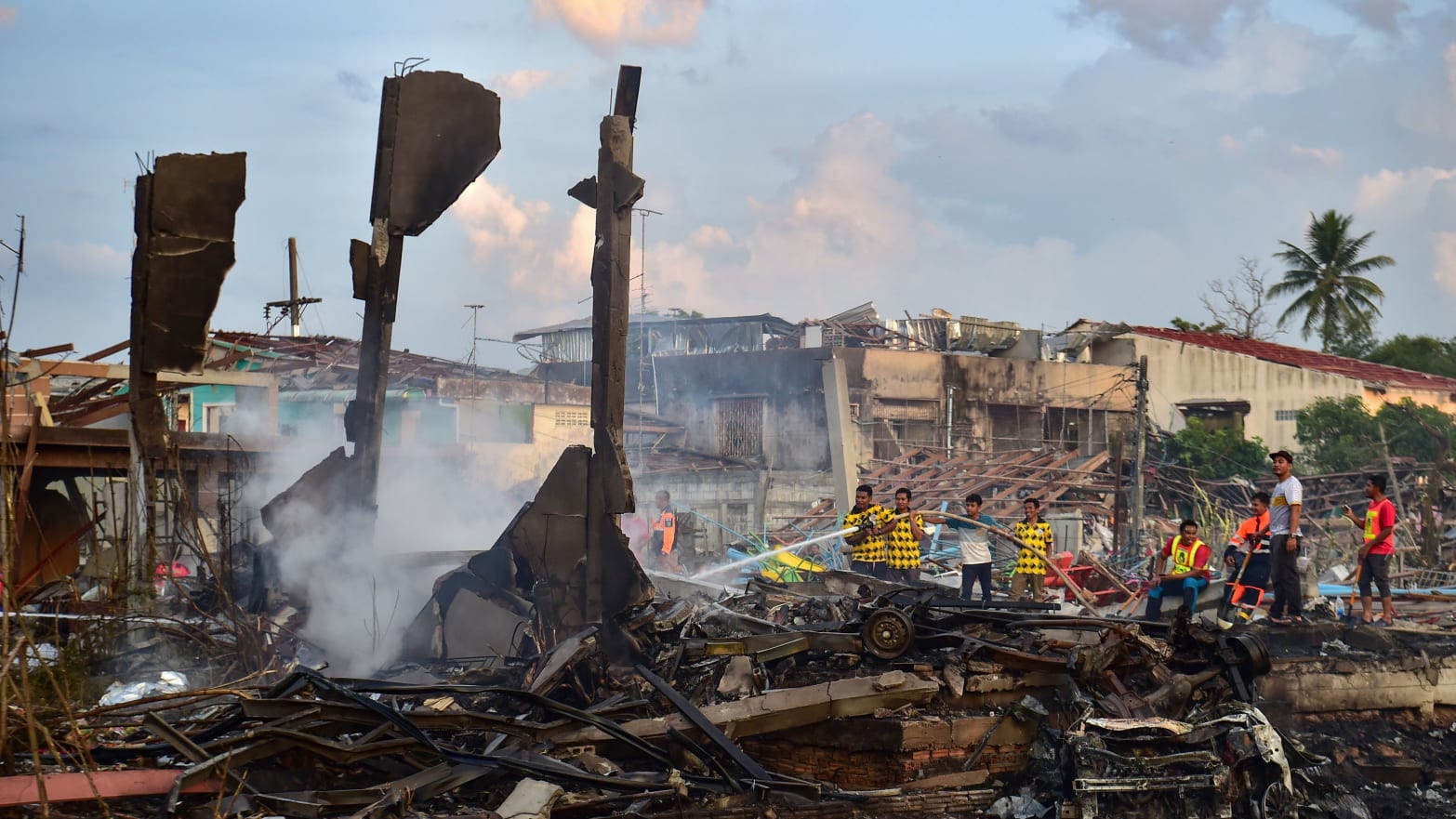Thai firefighters put out embers around destroyed homes after an explosion ripped through a firework warehouse, killing nine people and injuring more than 100, in Sungai Kolok district in the southern Thai province of Narathiwat on July 29, 2023.