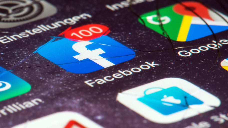 The Facebook logo on the jumped display of a smartphone indicates the number of unread notifications with the number 100.