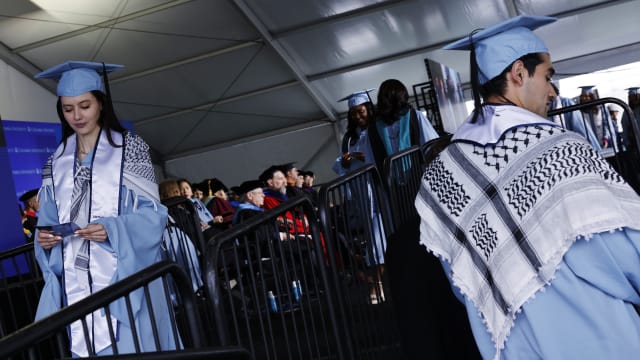 Students from the Columbia School of Professional Studies wear keffiyehs and celebrate after walking the stage during the schools graduation ceremony.