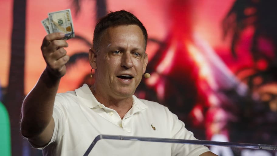 Peter Thiel holds hundred dollar bills as he speaks during the Bitcoin 2022 Conference