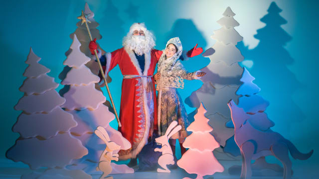 Russian Father Frost and Snow Maiden (Snegurochka) are standing together in a winter forest.