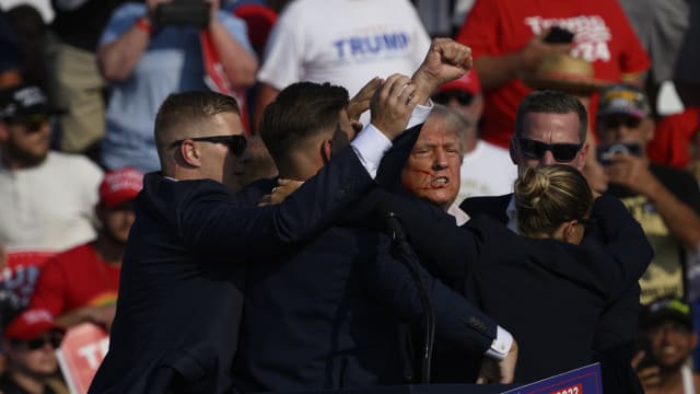 Donald Trump getting escorted off stage by Secret Service agents.