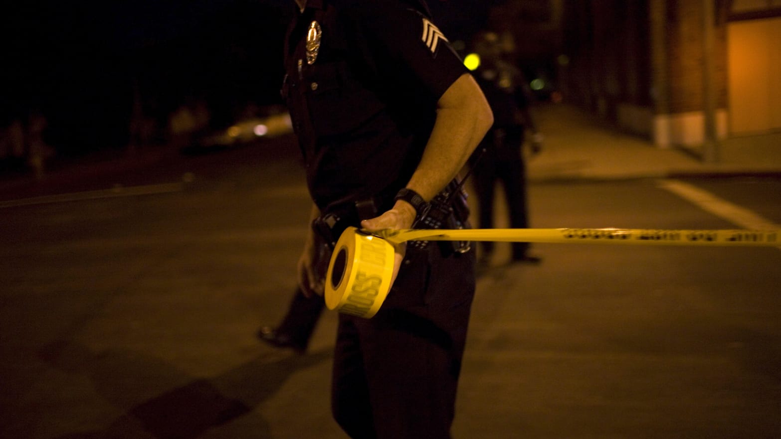 A police officer pulling crime scene tape.