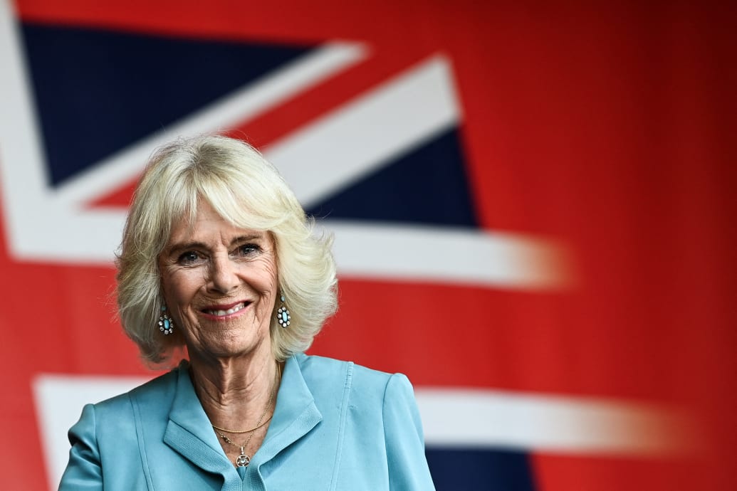 Queen Camilla smiles as she stands under a giant banner of the British Union flag during a visit to a festival in celebration of British and French culture and business at Place de la Bourse in Bordeaux, southwestern France, on September 22, 2023.