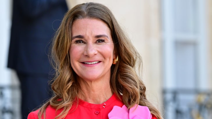 Melinda French Gates, pictured in a red dress appointed with a pink flower.