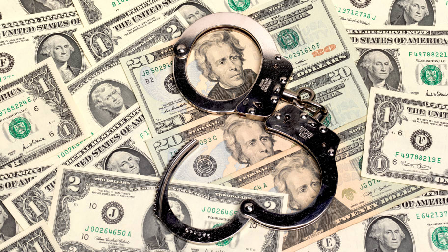 "a pair of open handcuffs sitting on top of a pile of us dollars of assorted denominations"