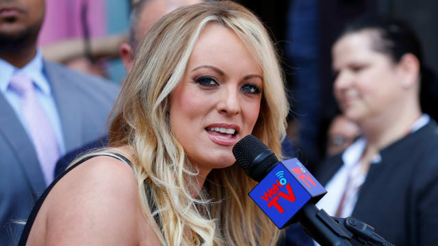 Stormy Daniels looks to her right while speaking into a handheld microphone.