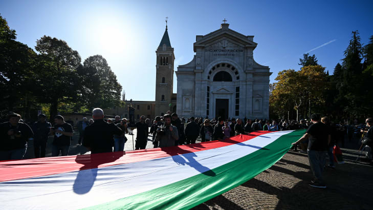 Participants, of a facists rally to commemorate the 100th anniversary of the March on Rome, hold a large Italian flag as they march to the San Cassiano cemetery, the burial place of Benito Mussolini, in Predappio, on October 30, 2022.