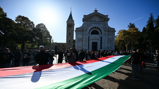 Participants, of a fascist rally to commemorate the 100th anniversary of the March on Rome, hold a large Italian flag as they march to the San Cassiano cemetery, the burial place of Benito Mussolini, in Predappio, on October 30, 2022.