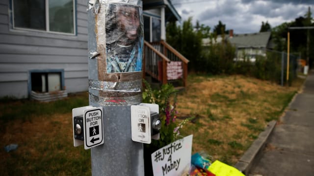 A photo of Manuel Ellis, who died in Tacoma police custody in March, is taped to a pole at a vigil site in Tacoma, Washington