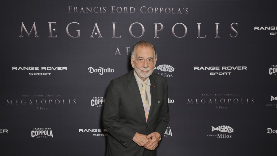 Francis Ford Coppola stands in front of a promotional background at the premiere of his film “Megalopolis”.