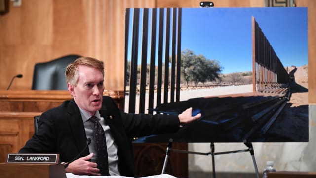 U.S. Senator James Lankford, R-OK, points to a photograph of a border fence.