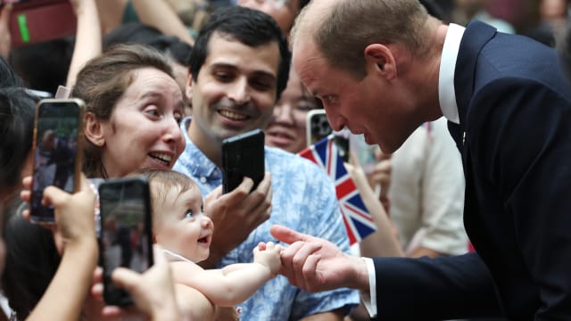 8 month old Albane Costa holds the finger of Prince William, Prince of Wales during his visit to the HSBC Rain Vortex at Jewel Changi Airport on day one of his visit to Singapore