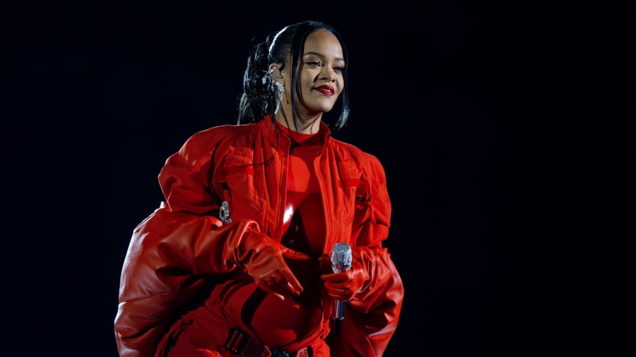 Rihanna smiles as she holds a microphone during Super Bowl performance.