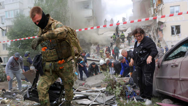 People remove debris while searching for survivors following the collapse of a section of an apartment block in the city of Belgorod, Russia, May 12, 2024. 
