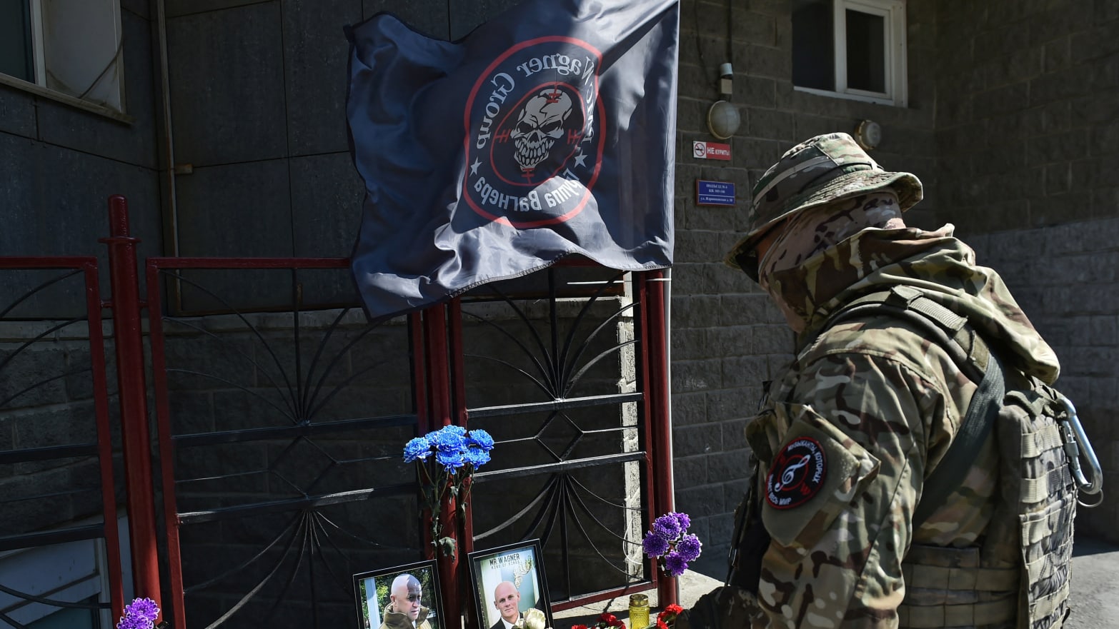A Wagner fighter stands in front of a makeshift memorial with portraits of mercenary chief Yevgeny Prigozhin and Wagner group commander Dmitry Utkin outside the local Wagner office in Novosibirsk, Russia, Aug. 24, 2023. 