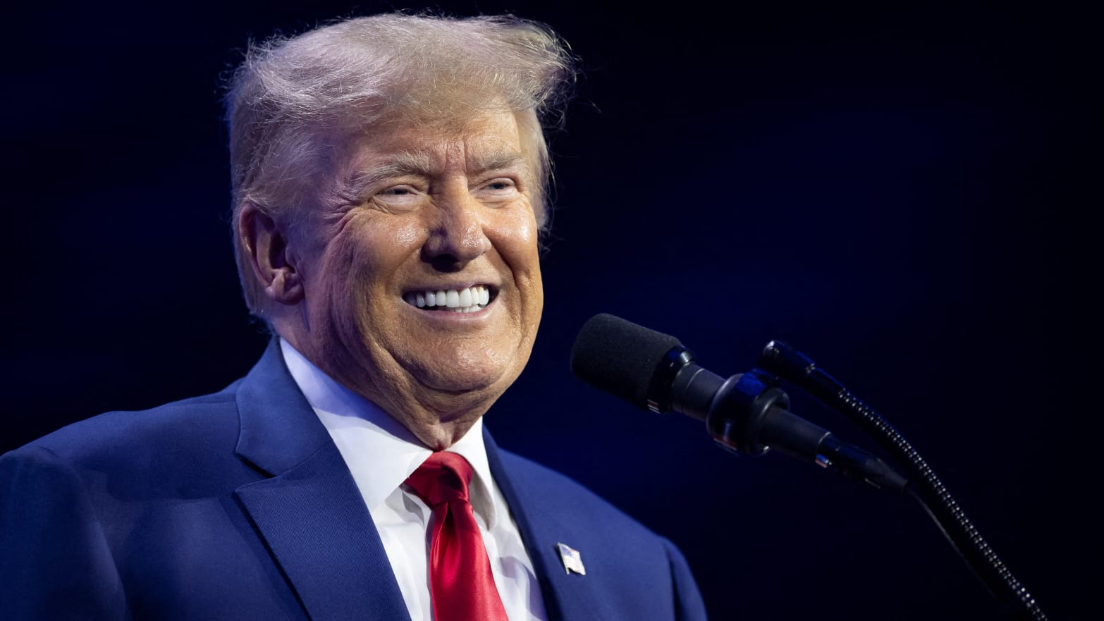 Donald Trump smiles on stage at a campaign event.