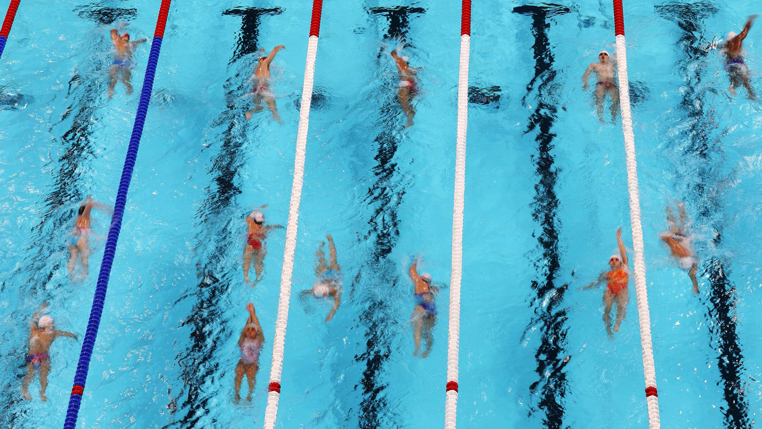 Swimmers swimming in the 2024 Paris Olympics Pool at Paris La Defense Arena.