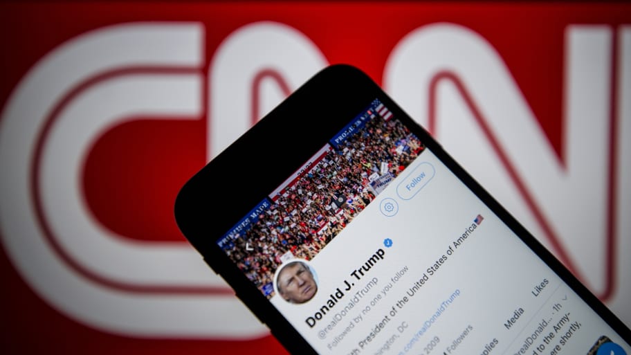 Donald Trump's Twitter timeline is seen on a smartphone against a backdrop with the CNN TV channel logo.