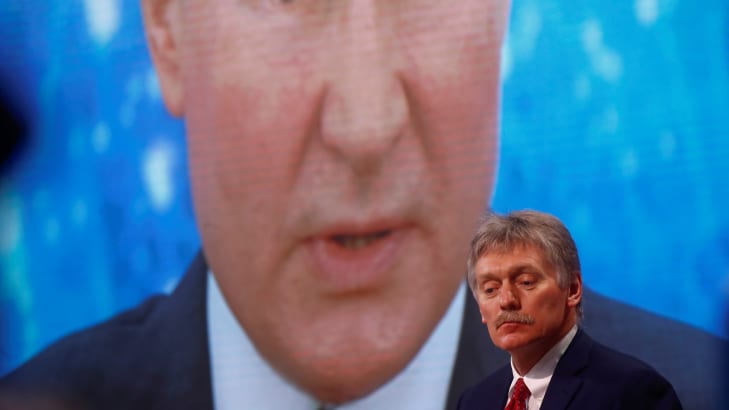 Kremlin spokesman Dmitry Peskov in front of an electronic screen showing Vladimir Putin