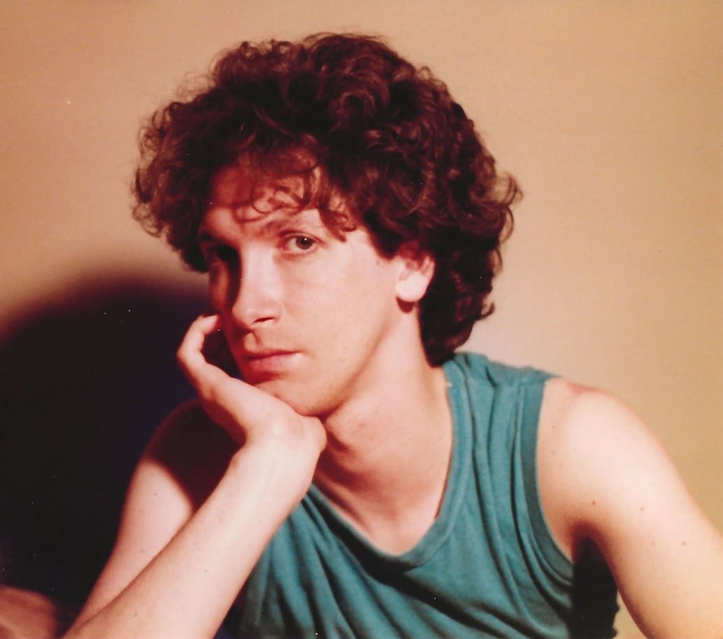 A portrait of a young Charles Busch in a green shirt