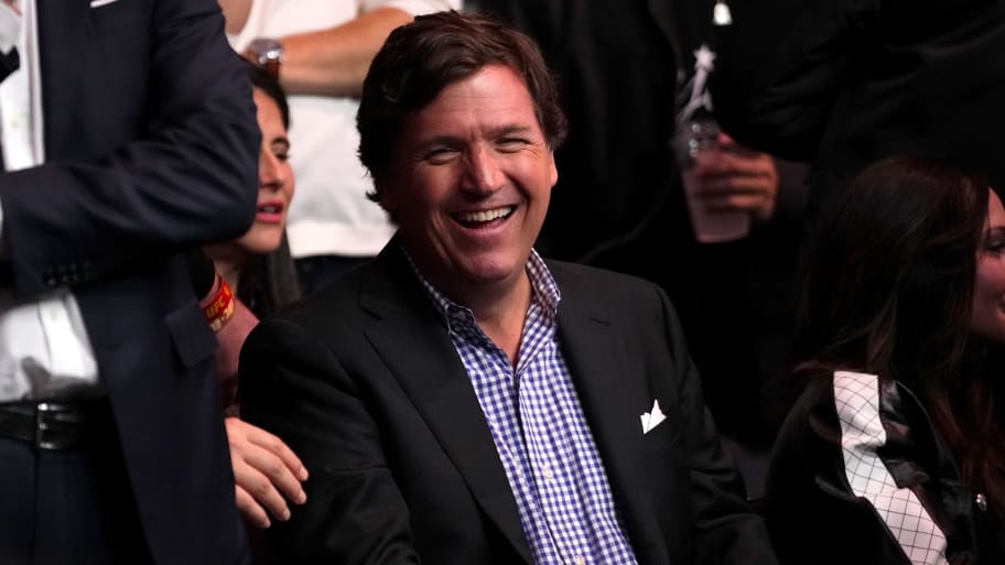 Tucker Carlson sitting down and laughing during a UFC event.
