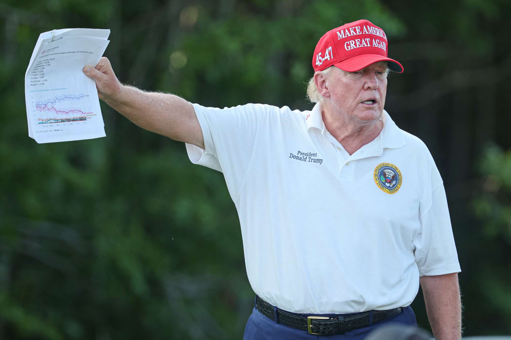 Former President Donald Trump holds papers showing the projections for the 2024 republican candidate primary polls during the first round of the LIV Golf Bedminster golf tournament