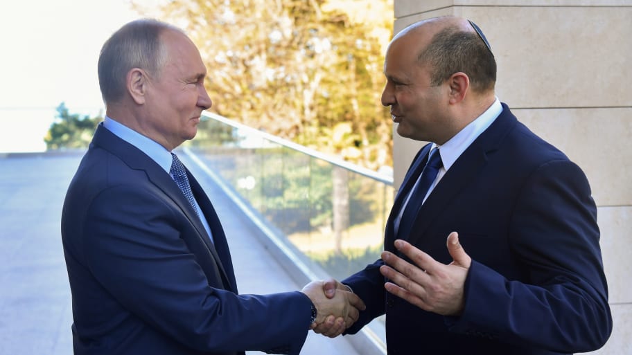 Naftali Bennett and Vladimir Putin shake hands.