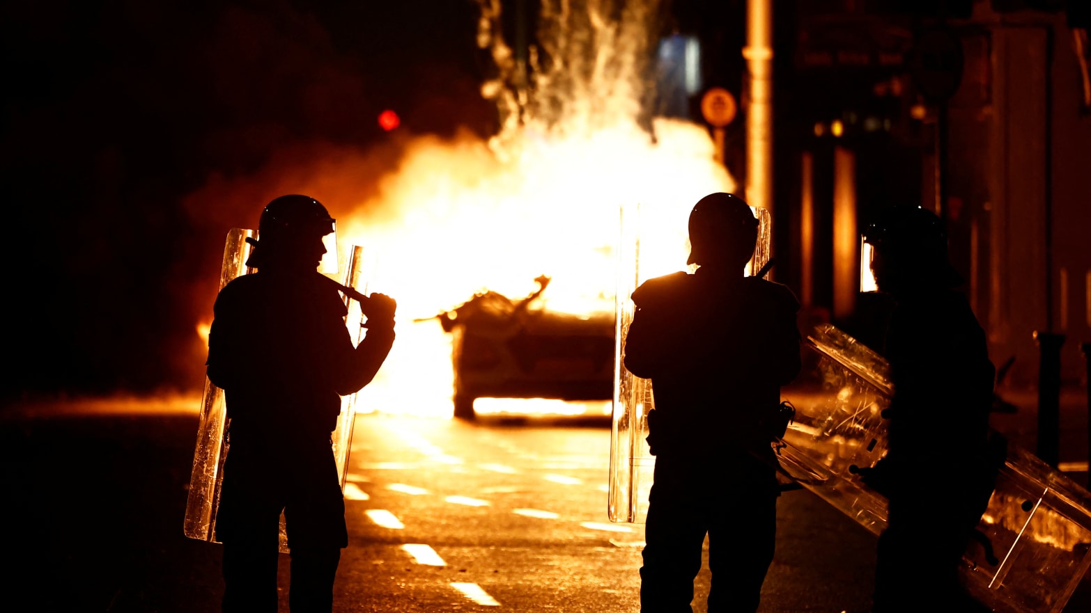 Riot police stands next to a burning police vehicle, near the scene of a suspected stabbing that left few children injured in Dublin, Ireland, November 23, 2023.