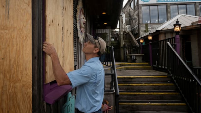 A man places plywood in front of a store ahead of the arrival of Hurricane Idalia in Cedar Key, Florida, Aug. 29, 2023. 