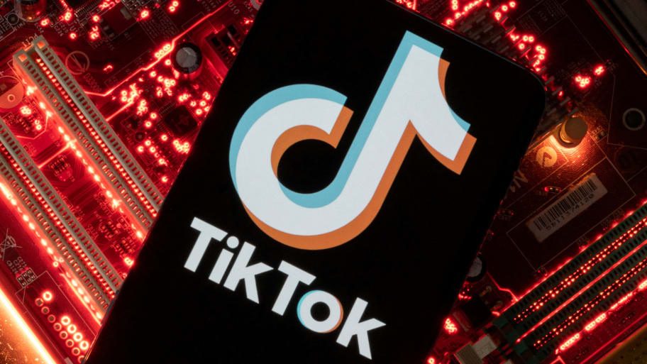 A smartphone with a displayed TikTok logo is placed on a computer motherboard.