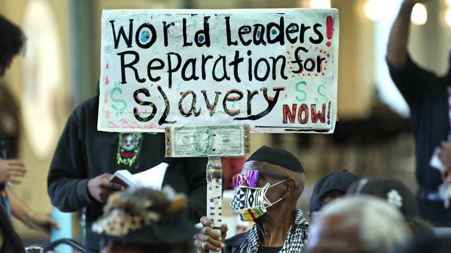 Man holds up sign at Reparations Task Force meeting