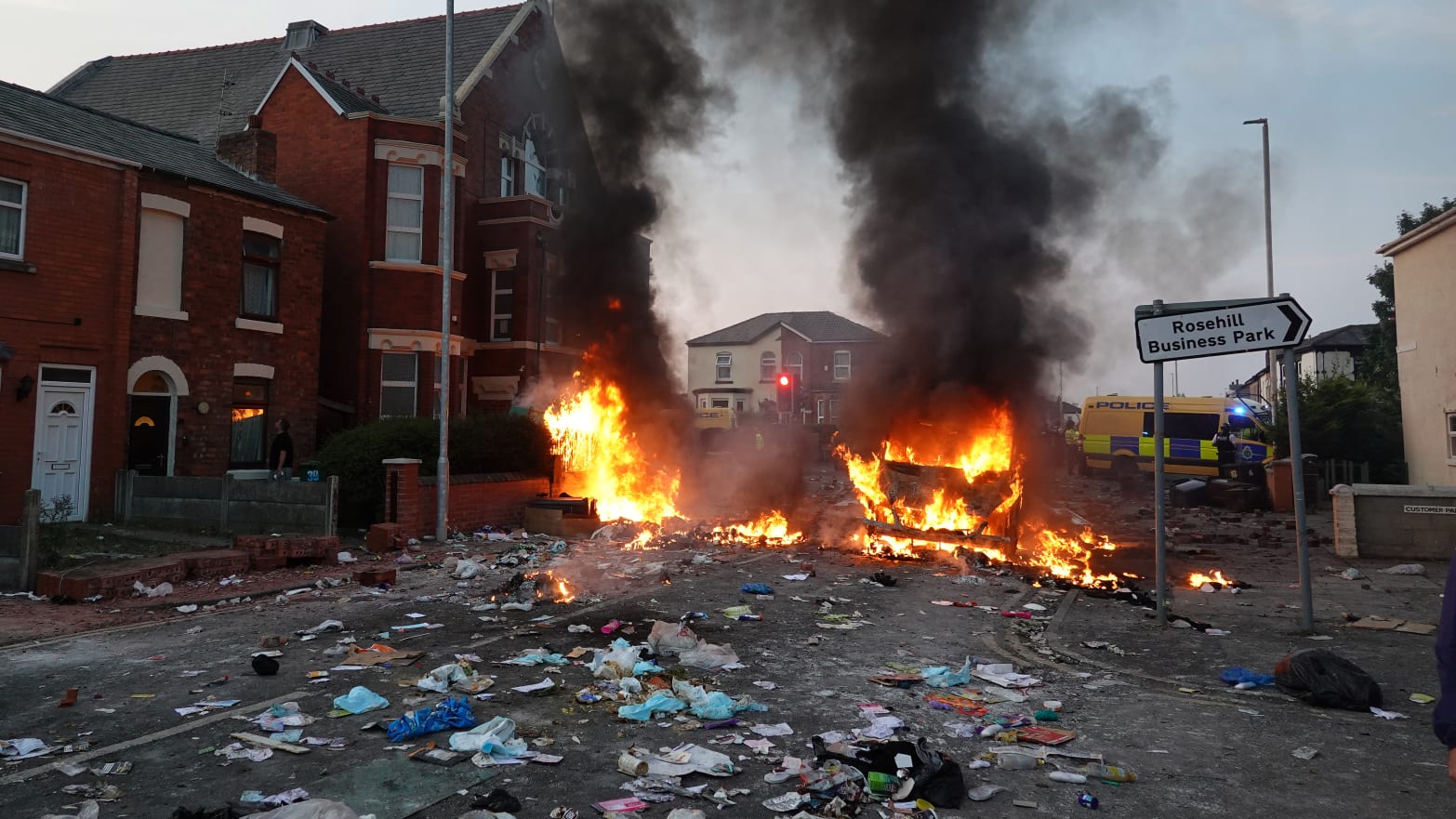 Riot police hold back protesters near a burning police vehicle after disorder broke out on July 30, 2024 in Southport, England. 