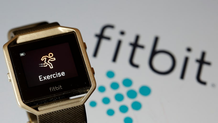 A Fitbit device in front of the Fitbit logo.