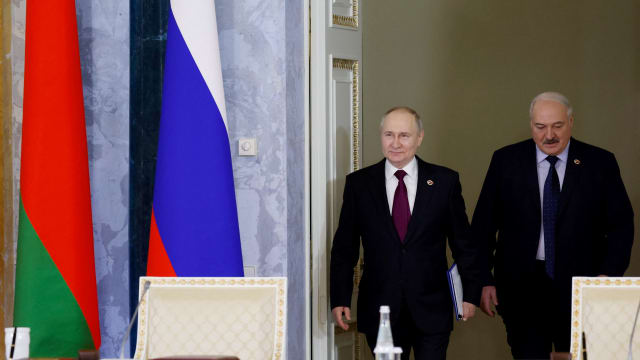 Russian President Vladimir Putin and Belarusian President Alexander Lukashenko walk through doors.