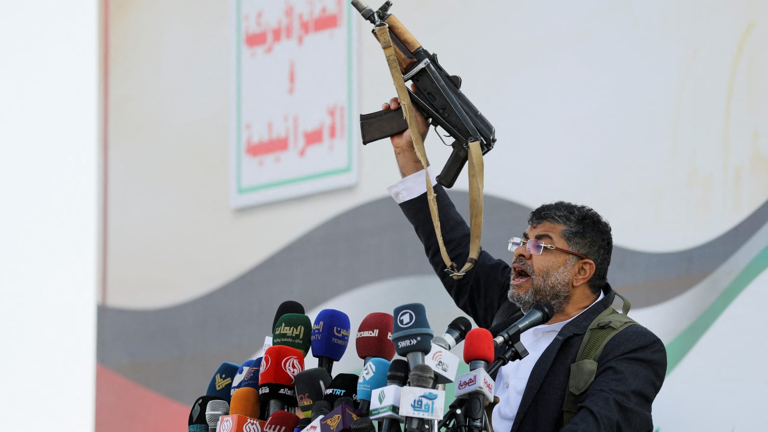 Mohammed Ali al-Houthi, a member of the Houthi supreme political council, speaks while holding a gun, as supporters of the Houthi movement rally to denounce air strikes launched by the U.S. and Britain on Houthi targets, in Sanaa, Yemen