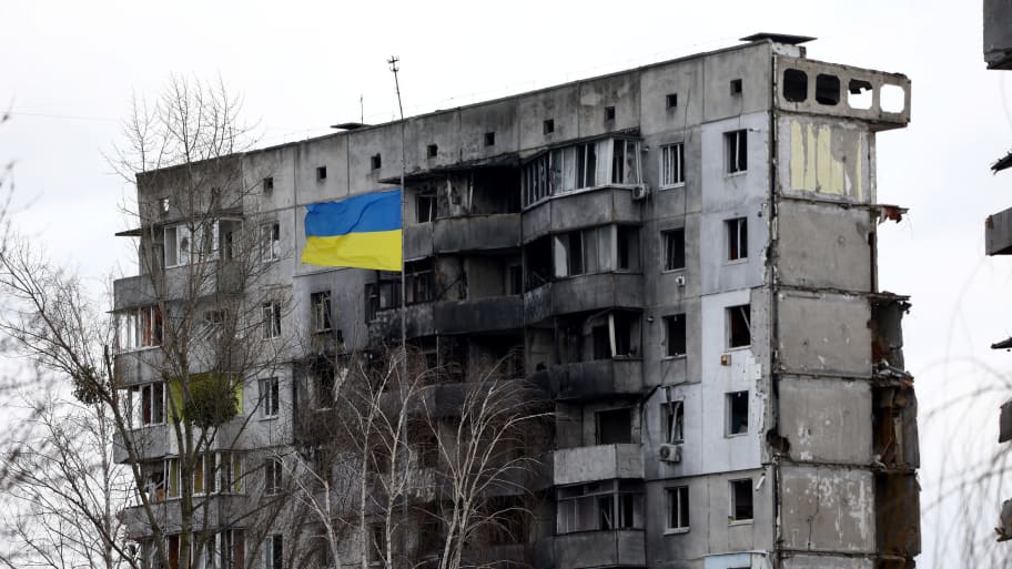 A Ukrainian national flag flies in front of a destroyed residential building amid Russia's invasion of Ukraine.