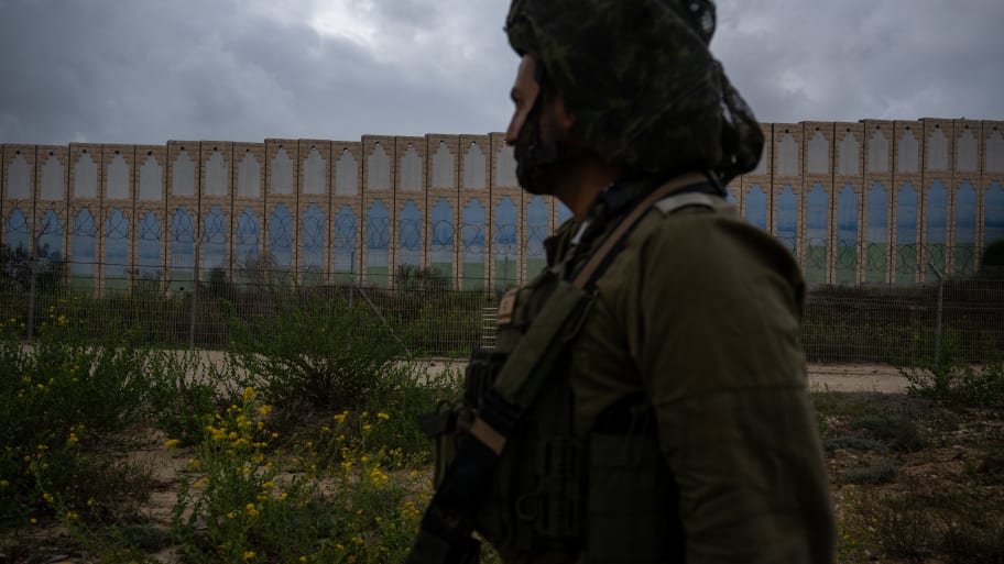 An IDF officer walks past the protective barriers near the border fence with the Gaza Strip